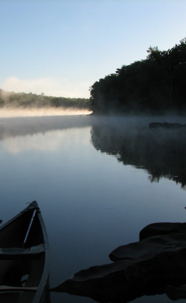 A canoe in a river with mist rising from the water