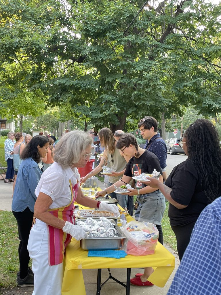 people serving food at a baked potato bar